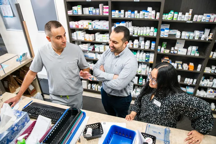 Kyro Maseh, pharmacist and founder, speaking with teammates at the pharmacy counter